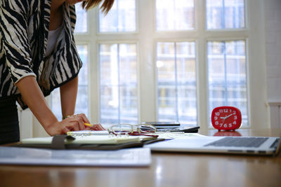 Midsection of woman reading book on table