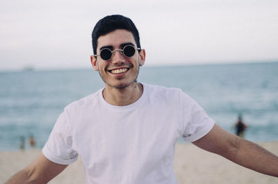 Portrait of smiling young man standing against sea