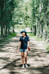 Full length of woman walking on road amidst trees in forest