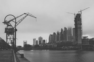 Cranes at construction site in city against sky