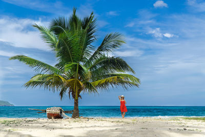 Mid distance view of woman standing at beach against sky