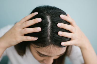 Close-up of woman showing hair with hands against wall