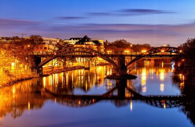 Illuminated bridge over river at night