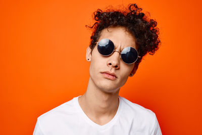 Portrait of man wearing sunglasses against orange background