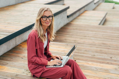 Modern business woman works remotely on a laptop in a public park.
