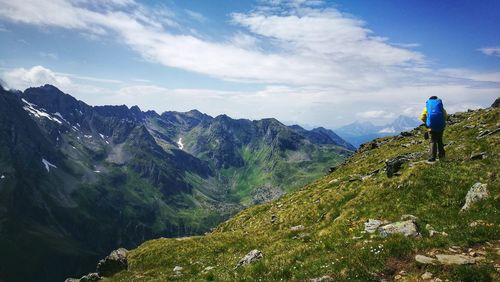 Rear view of hiker standing on mountain against sky