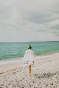 Rear view of woman standing at beach