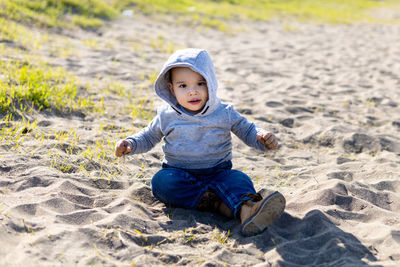 Portrait of cute boy sitting on sand at beach