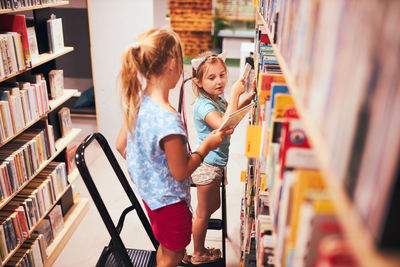 Side view of young woman standing in library