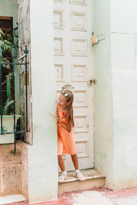 Woman standing against door of building