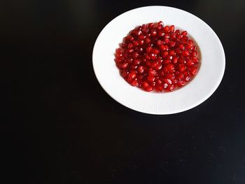 Close-up of strawberries in plate on table against black background