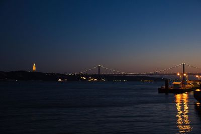 Illuminated bridge over river against sky