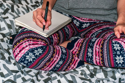 Low section of person wearing canvas shoes on bed