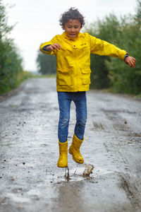 Boy jumping through muddy puddles in the rain