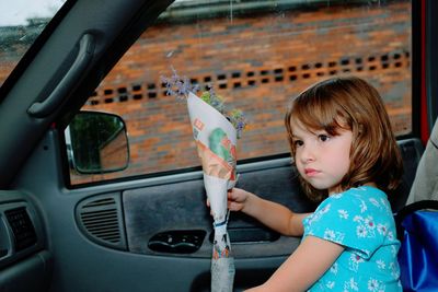 Close-up of girl holding flower while sitting in car