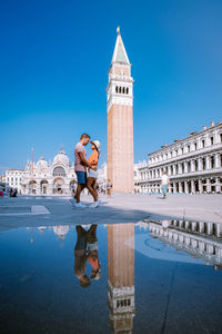 Reflection of building in water against clear blue sky