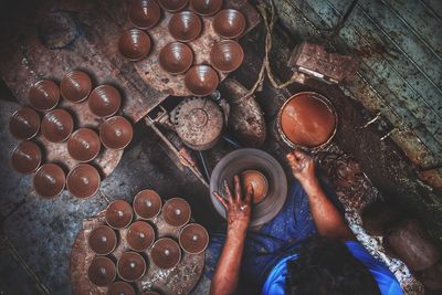 High angle view of man preparing clay bowl