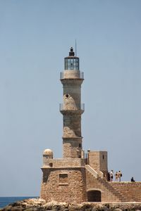 Lighthouse by sea against clear sky