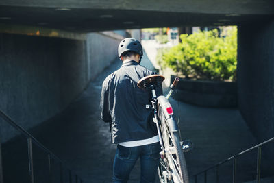 Rear view of businessman carrying bicycle while moving down steps