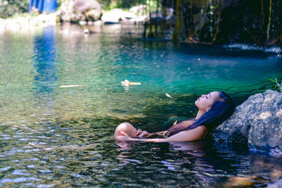 Woman lying on rock in lake