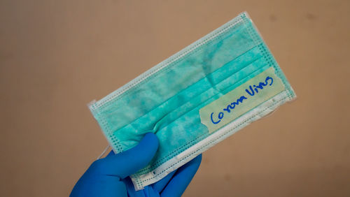 Close-up of hand holding paper against white background