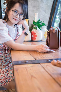 Midsection of woman holding smart phone while sitting on table