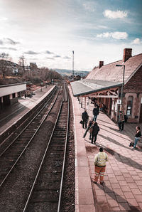 People waiting at railroad station against sky