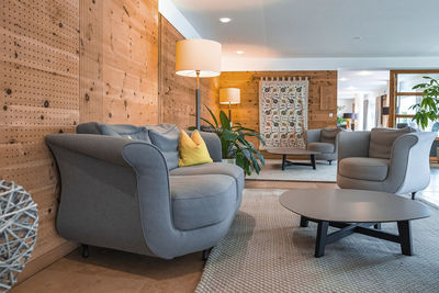 Sofa arranged with armchairs and table in decorated lobby at ski resort