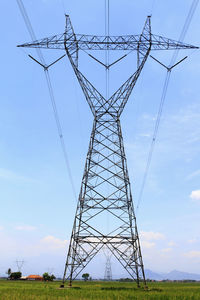 Low angle view of electricity pylon on field