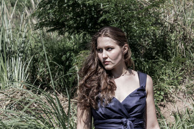 Portrait of young woman standing against trees