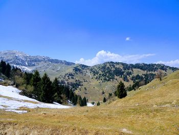 Scenic view of landscape and mountains against blue sky