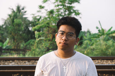 Portrait of young man sitting by railroad track