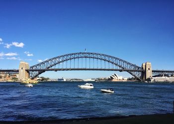 View of bridge in city against blue sky