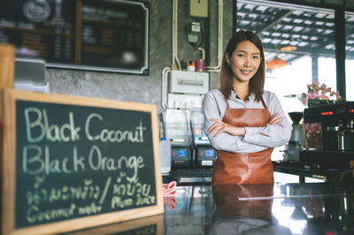 Portrait of smiling female owner standing in coffee shop