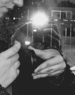 Midsection of man photographing camera at night