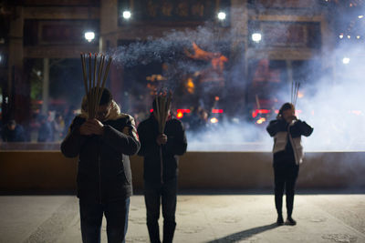 Rear view of people photographing at night