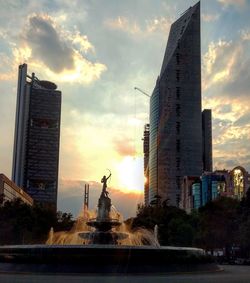 Statue in city against sky during sunset