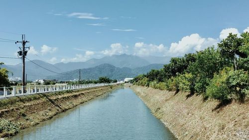 Scenic view of canal amidst trees against sky