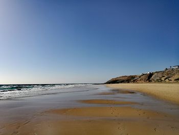 Scenic view of beach against clear blue sky