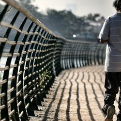 Rear view of man walking on footbridge