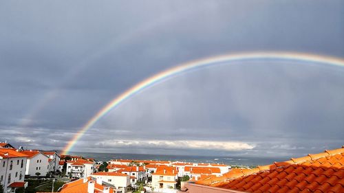 Rainbow over buildings in city against sky