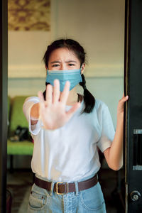 Portrait of girl wearing flu mask gesturing at home