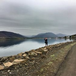 Rear view of woman photographing river against sky