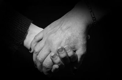 Close-up of hand holding hands over black background