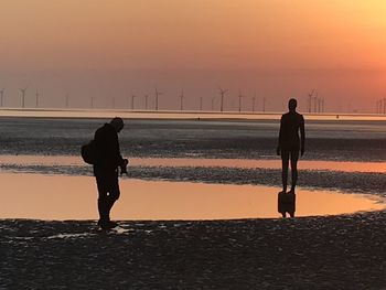 Full length of man on beach against sky during sunset