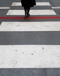 Low section of woman crossing on zebra crossing