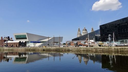 Buildings by river against sky in city