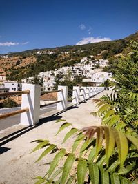 Scenic view of town by mountains against blue sky