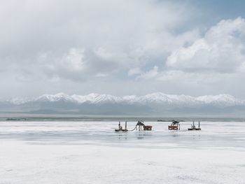 Machinery on salt lake against sky during winter