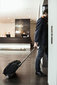 Businessman with luggage entering elevator in hotel